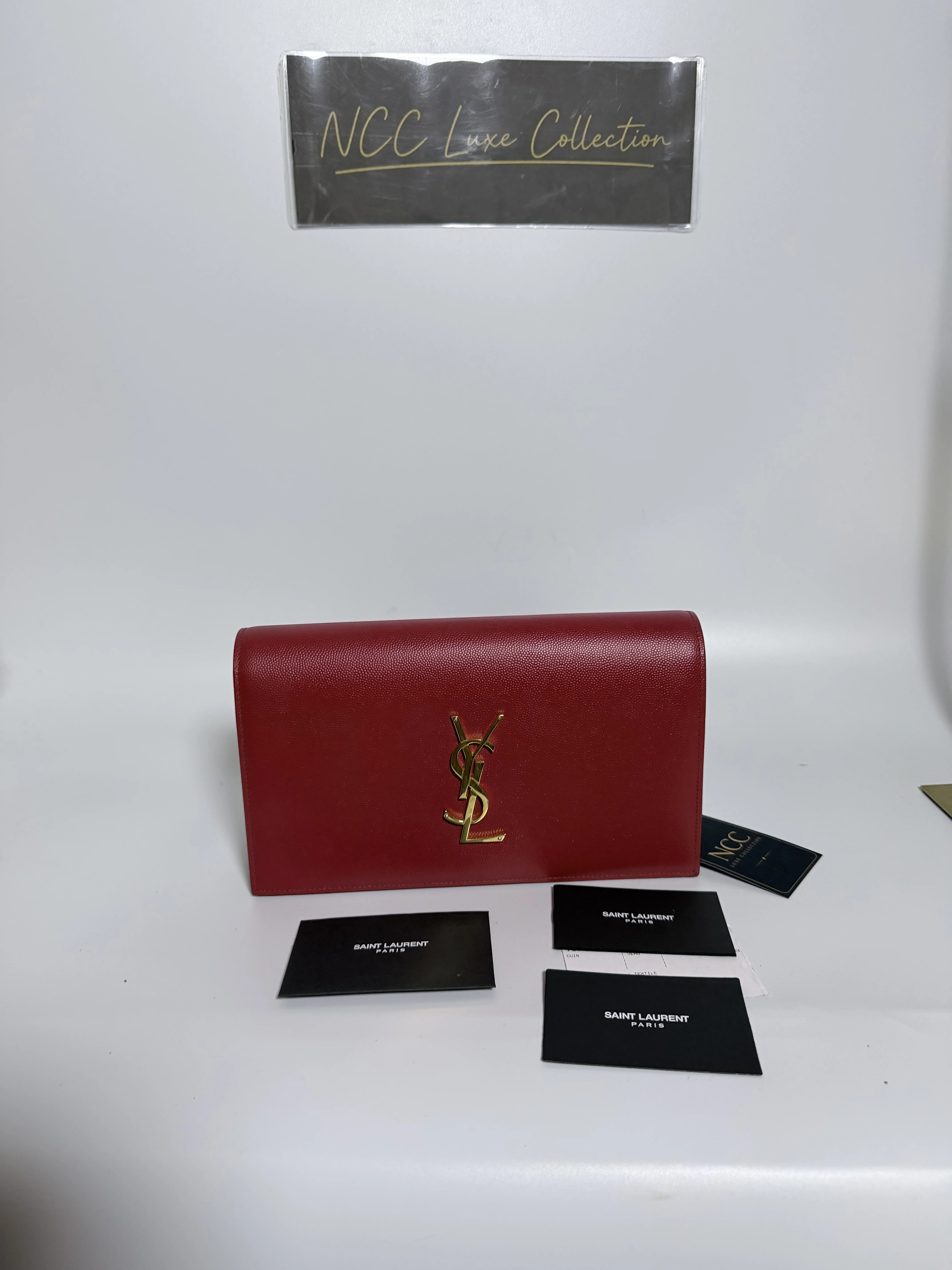 Saint Laurent Kate Monogram Clutch in red leather featuring prominent gold-tone hardware.